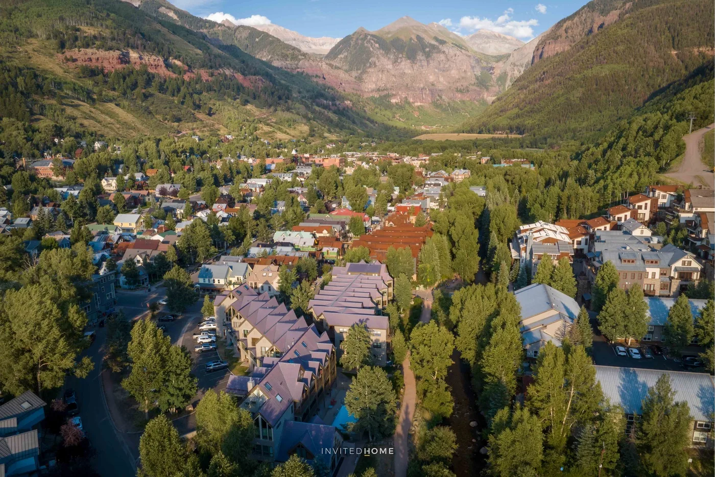 Vista aérea de un pueblo en un valle montañoso rodeado de laderas boscosas.