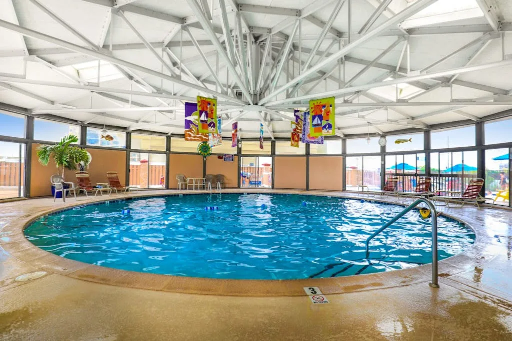 An indoor swimming pool sits beneath a bright roof with exposed beams.