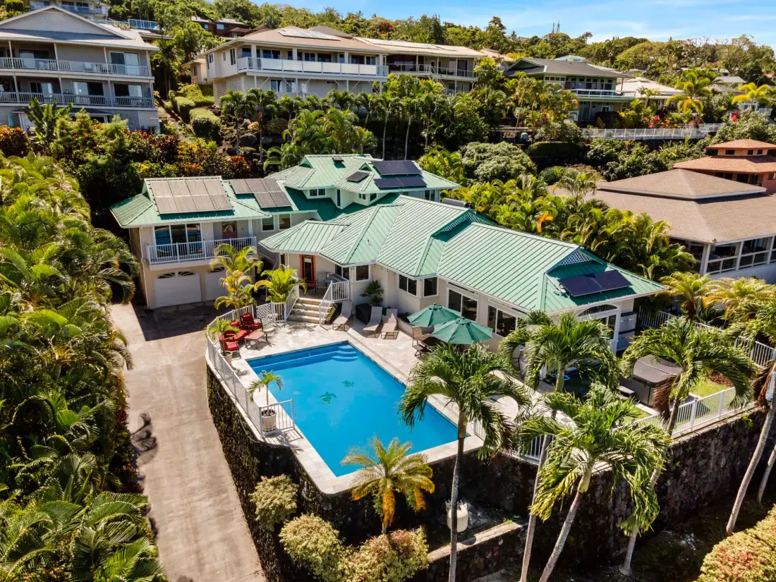 Vista aérea de una residencia con piscina rodeada de vegetación tropical.