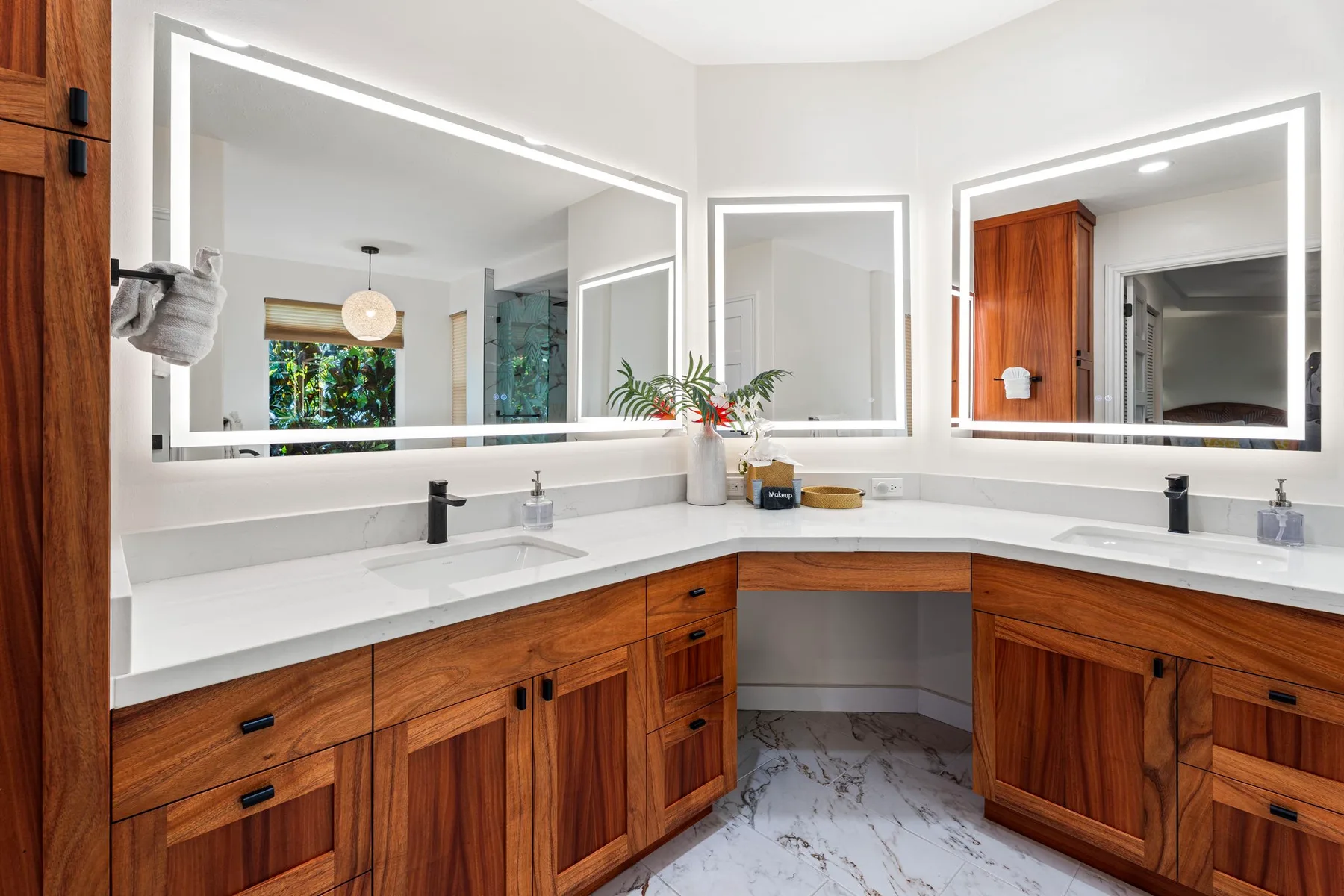 Un tocador de baño luminoso con gabinetes de madera y espejos grandes.