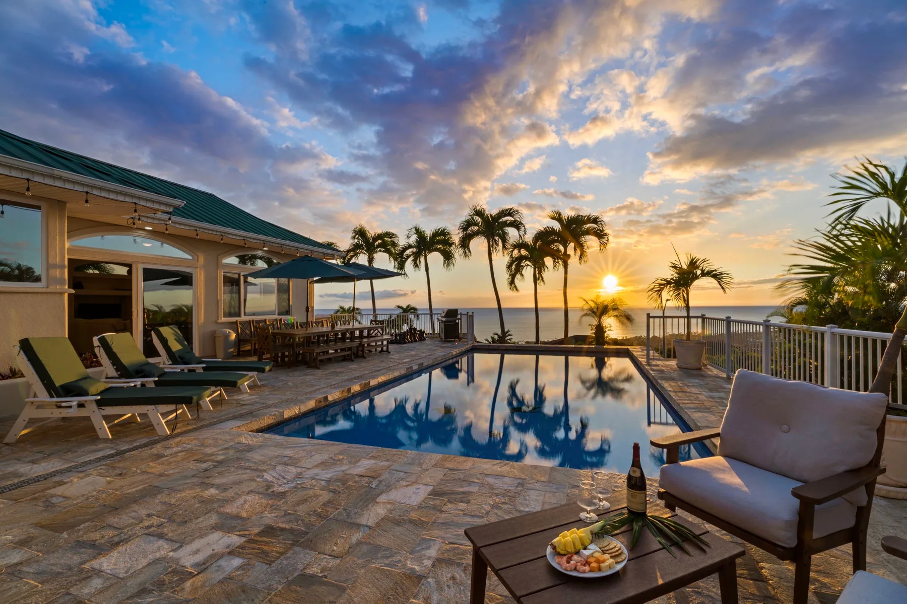 Un patio junto a la piscina con asientos al aire libre da al océano al atardecer.
