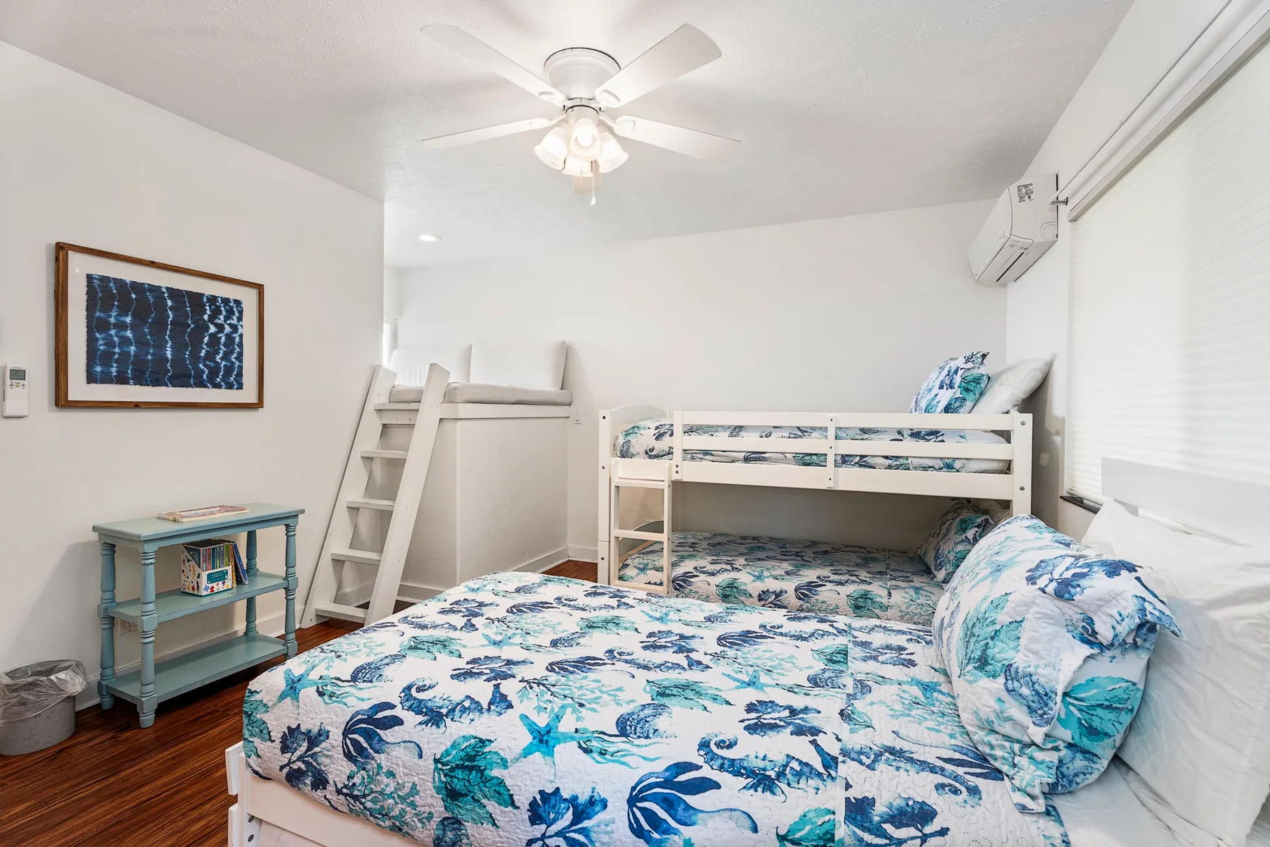 Un dormitorio luminoso con una cama estampada de flores y una litera.