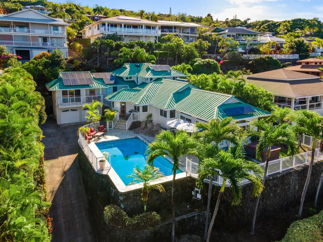 Vista aérea de una propiedad tropical con edificios de techos verdes y una piscina.