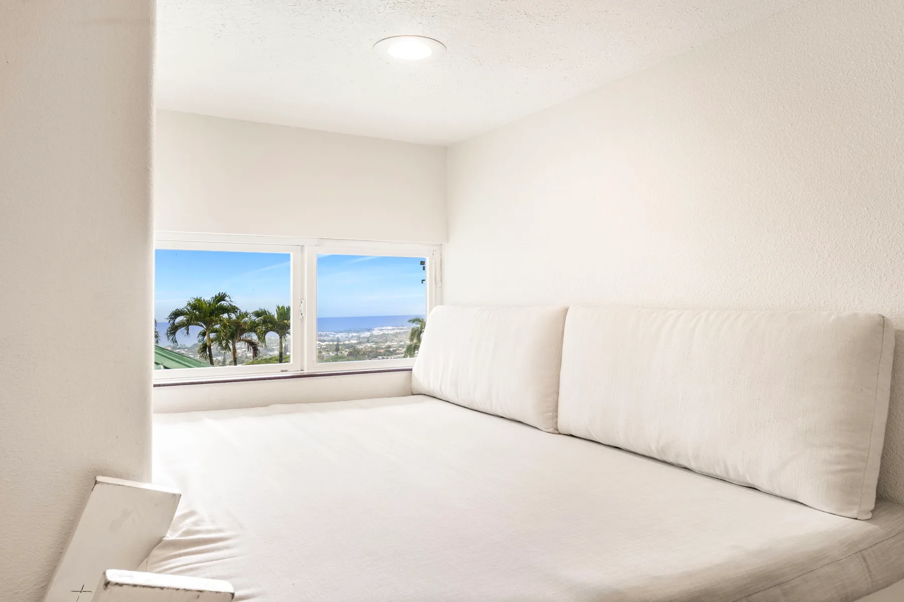 Un dormitorio luminoso con una cama grande junto a ventanas con vistas a la costa.