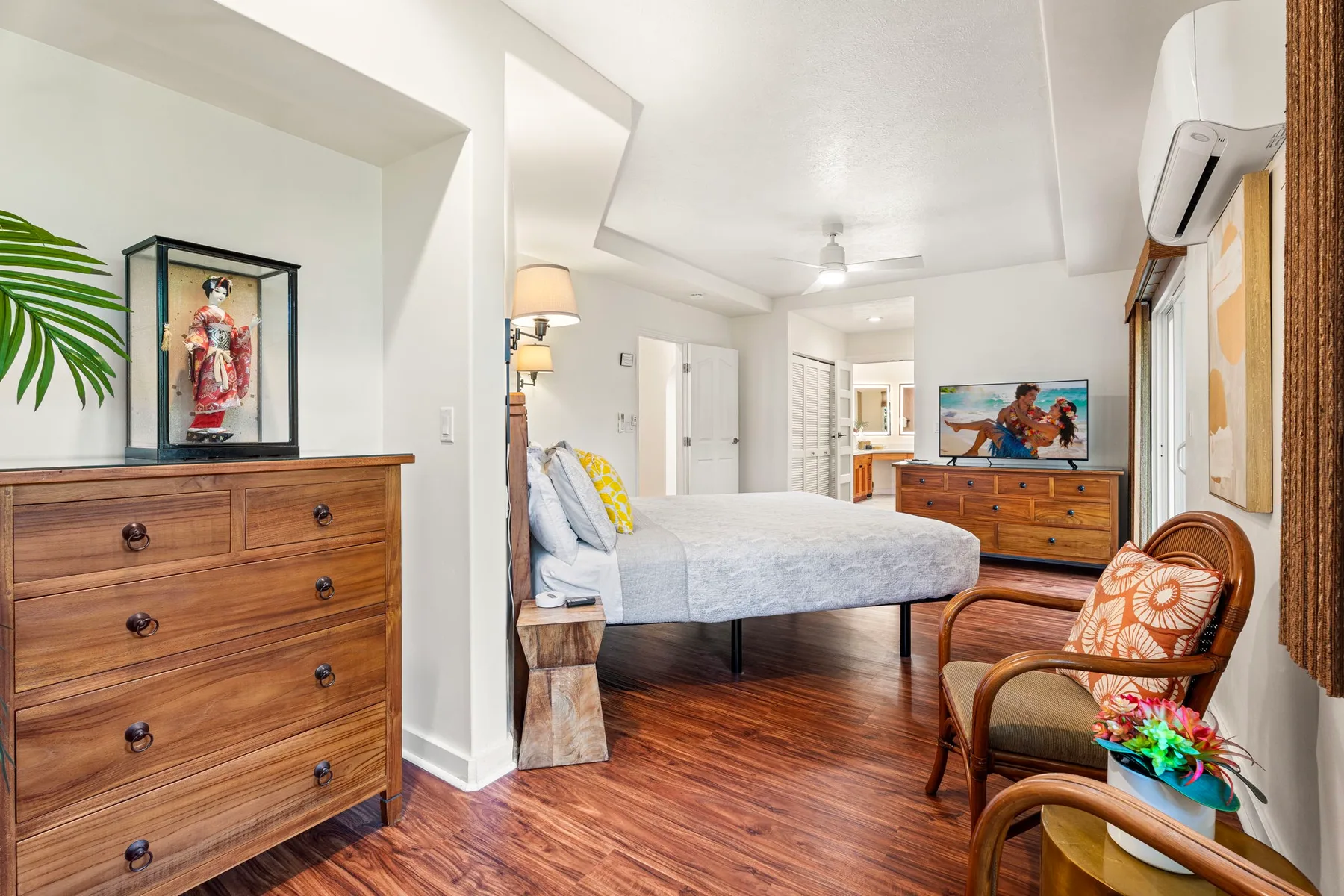 Un dormitorio luminoso con una cama, cómodas de madera y una silla.
