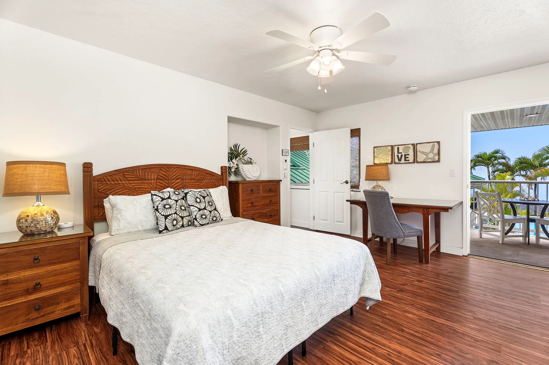 Un dormitorio con una cama, muebles de madera y una puerta abierta al balcón.