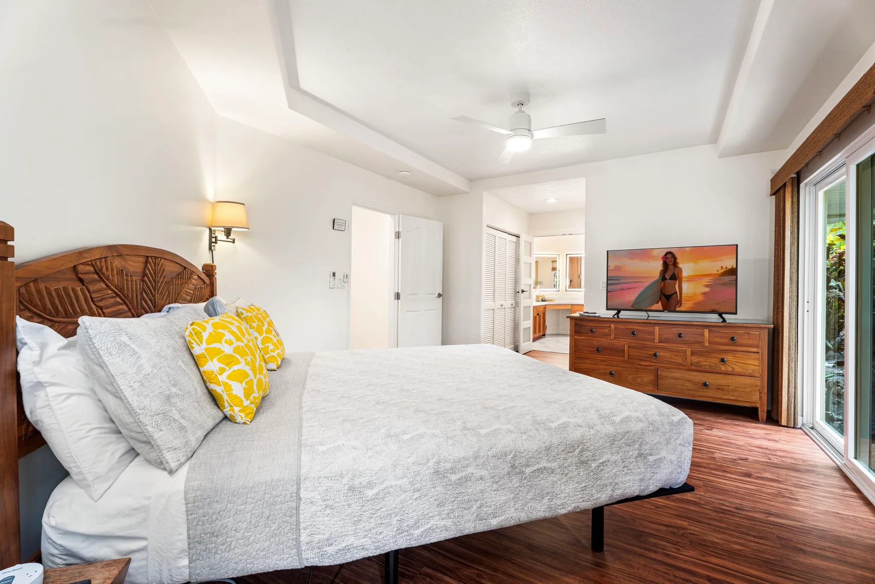 Un dormitorio luminoso con una cama grande y una cómoda de madera.
