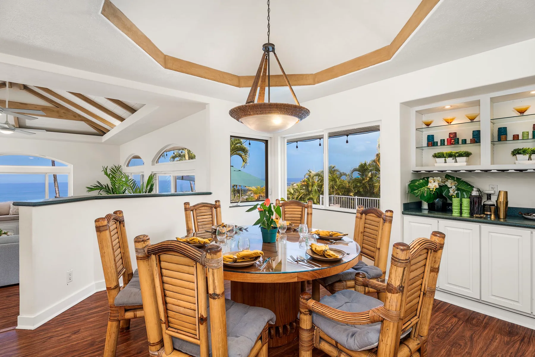 Un comedor luminoso cuenta con una mesa redonda junto a grandes ventanas con vistas a la vegetación y el océano.