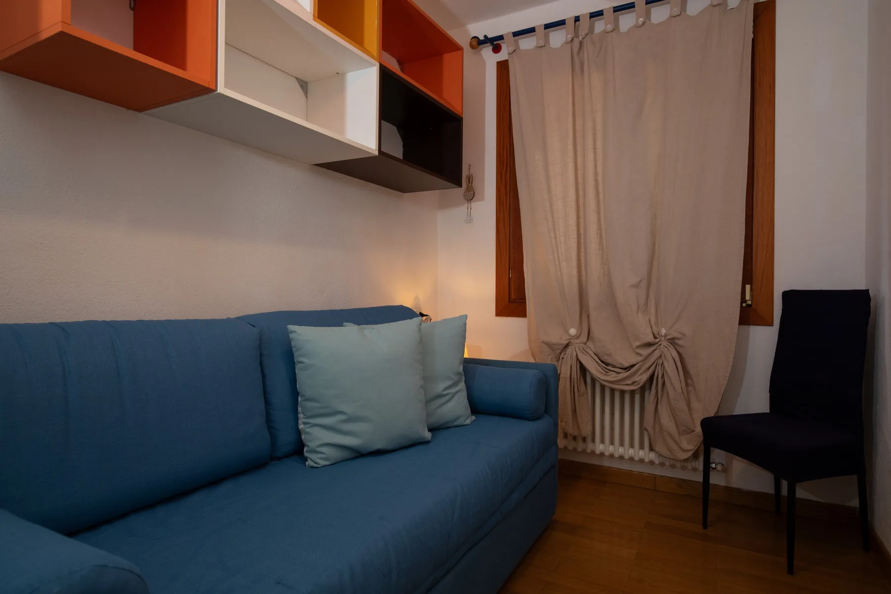 Una sala de estar con asientos azules junto a una ventana con cortinas.