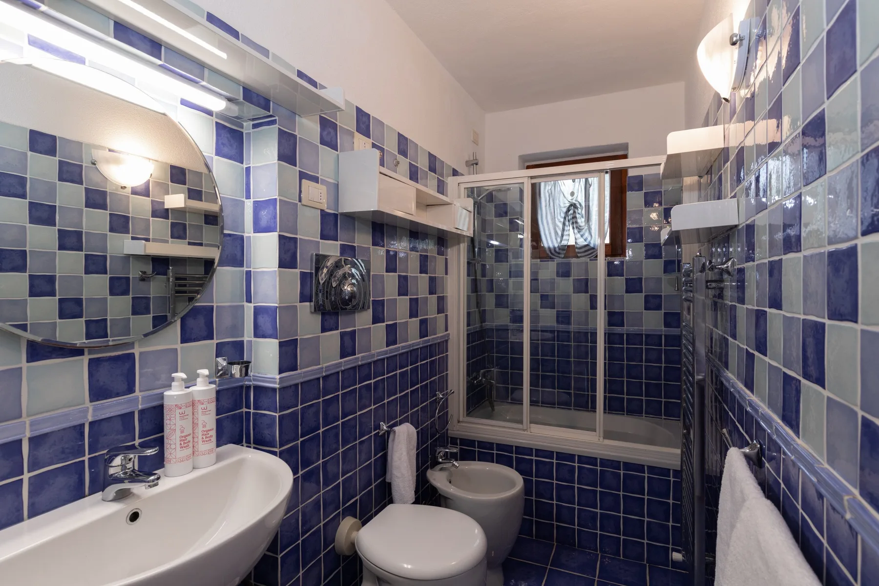 Un baño alicatado con lavabo, inodoro y ducha de vidrio.