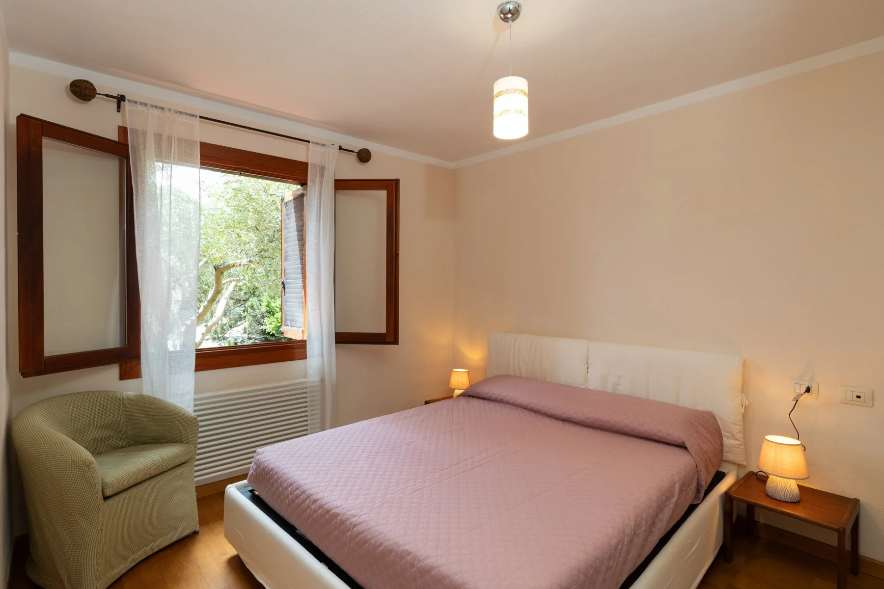 Un dormitorio con una cama grande, mesitas de noche y una ventana con cortinas.