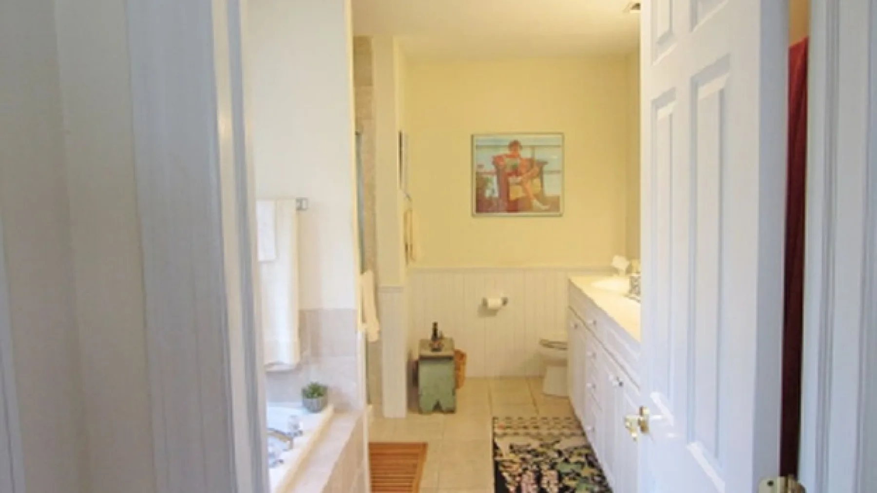 A bathroom with a bathtub, a vanity, and a framed picture on the wall.