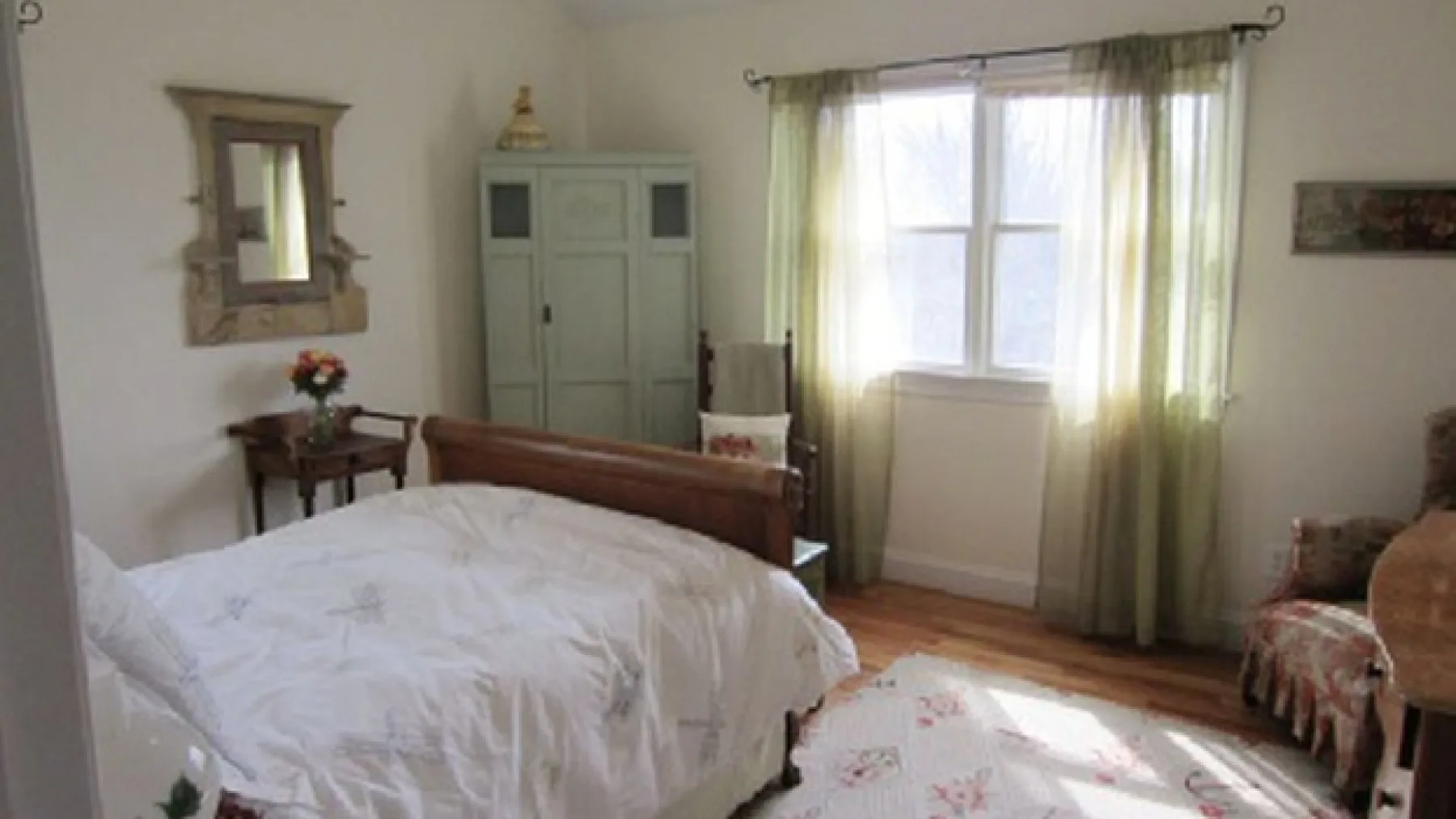 A bedroom with a bed, wardrobe, and a sunlit window.