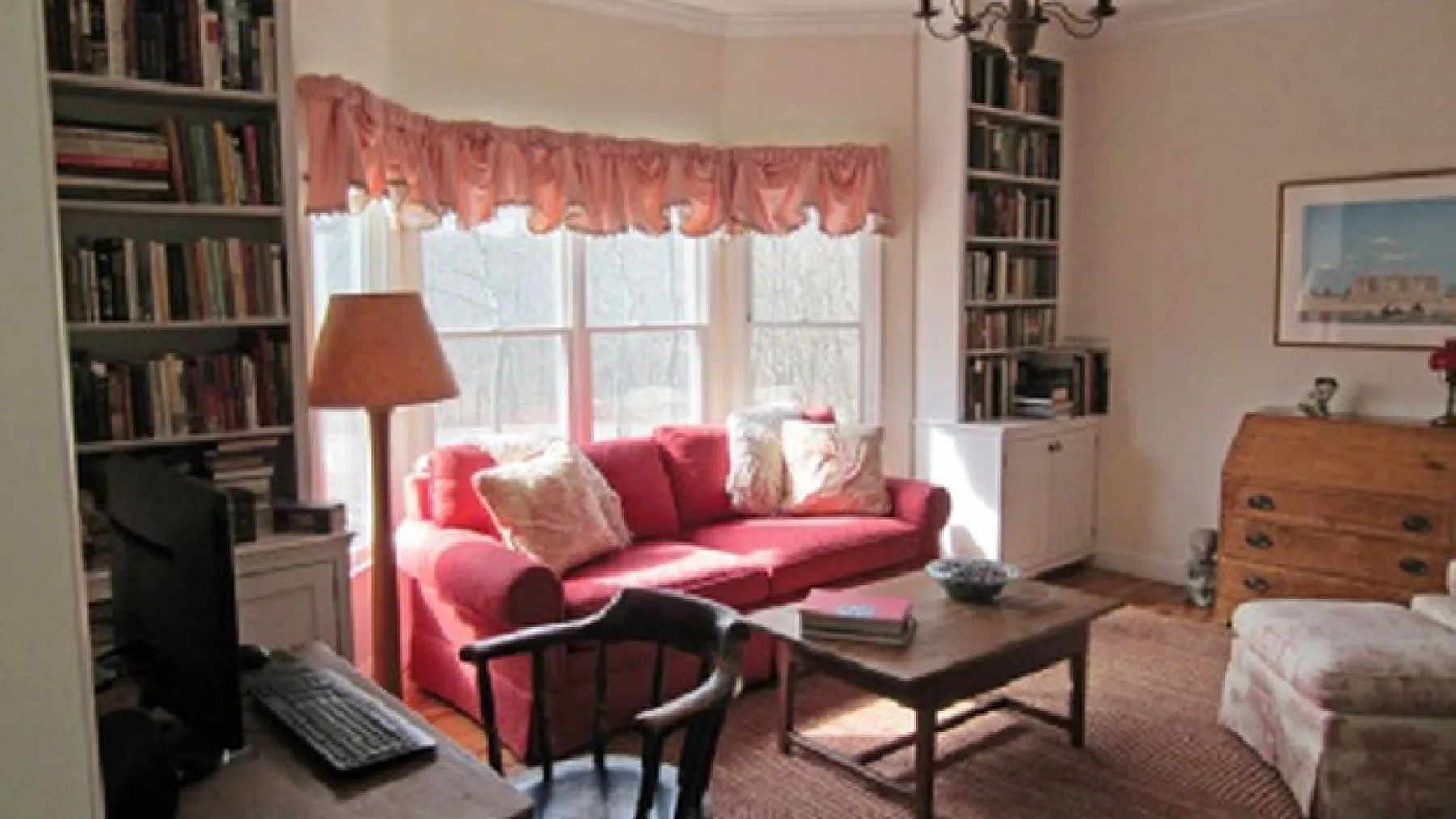A living room with red seating, bookshelves, and a coffee table.
