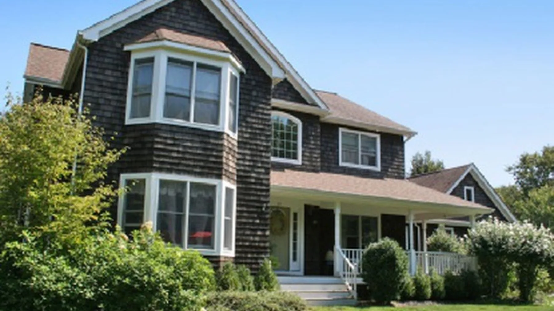A large house with a covered front porch and prominent bay windows.