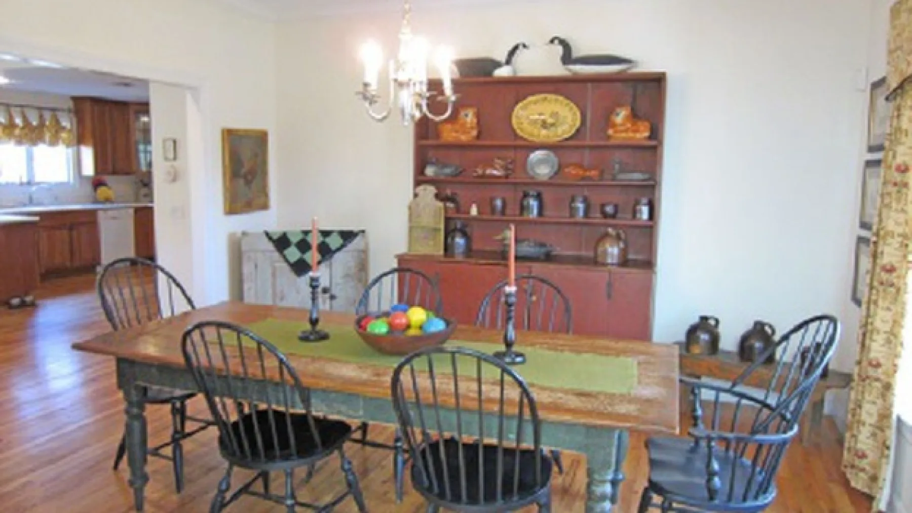 A dining room with a wooden table and chairs beneath a chandelier.