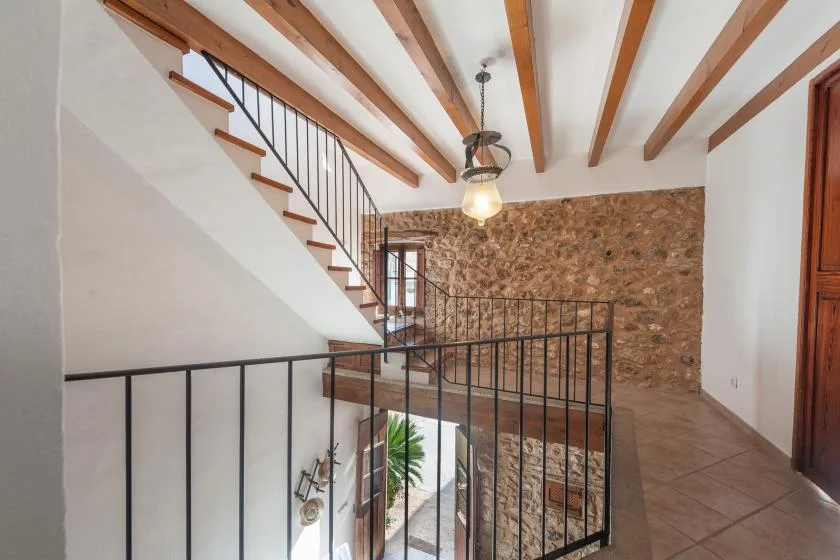 An interior landing with a staircase, metal railings, and exposed ceiling beams.