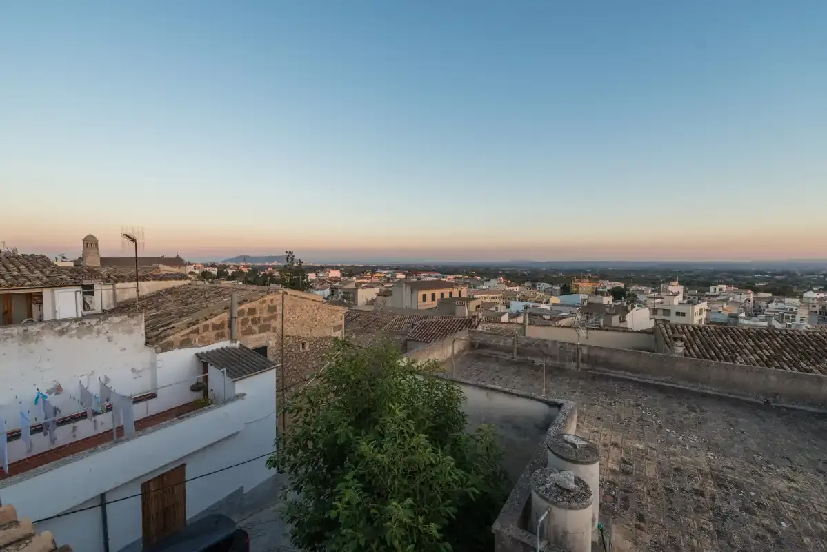 A townscape of rooftops and buildings beneath a broad evening sky.