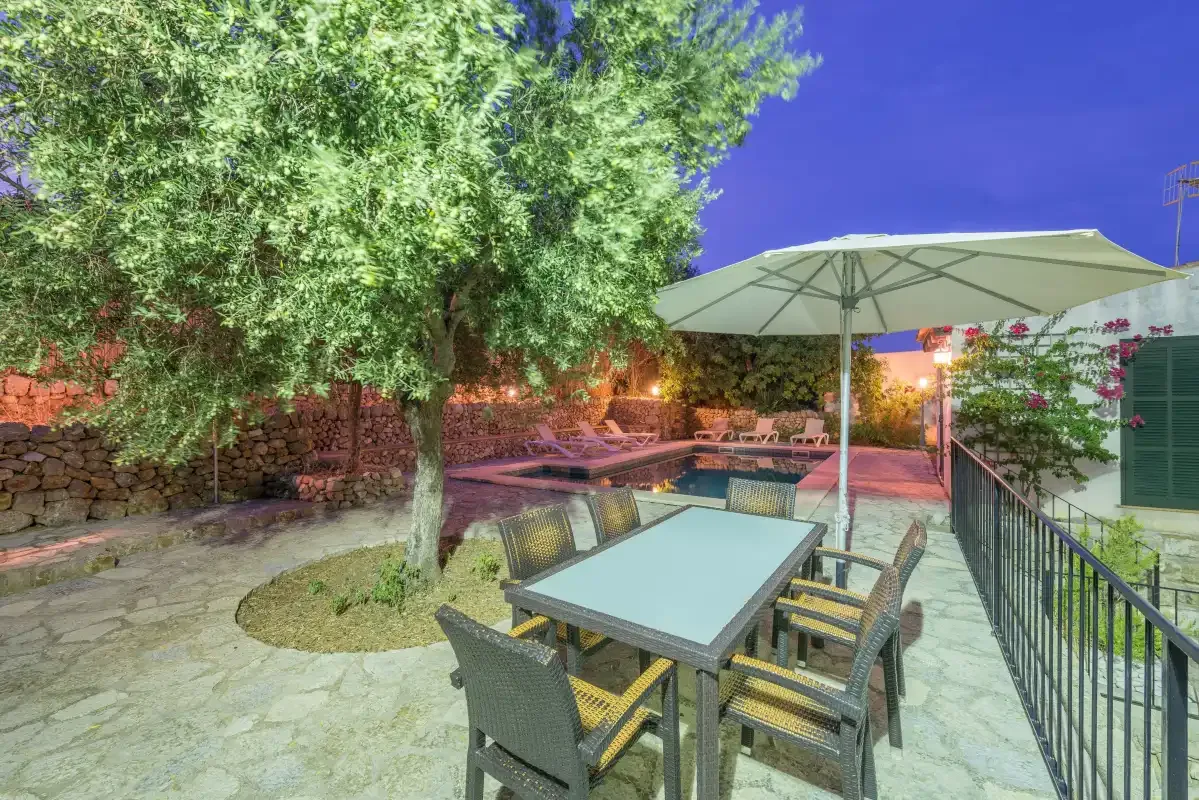 An outdoor dining area with a table and seating beneath a large umbrella.