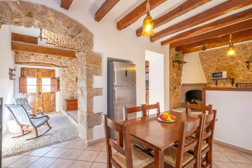 A rustic dining area with a wooden table beside a stone fireplace.