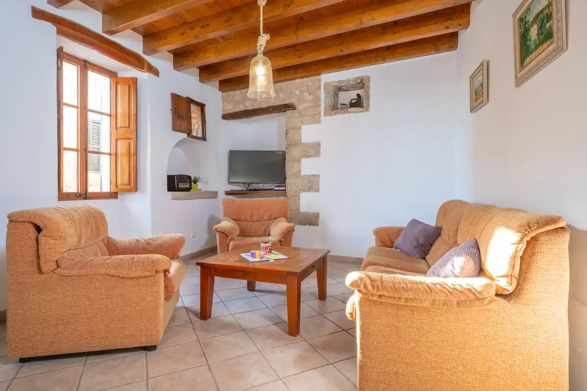 A living room with seating around a wooden coffee table and a television.