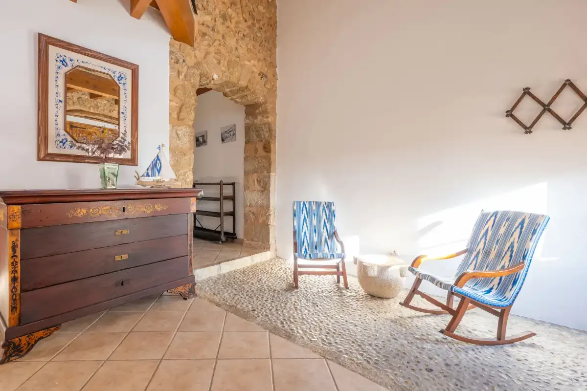 A bright sitting area has blue-striped seating beside a stone archway.
