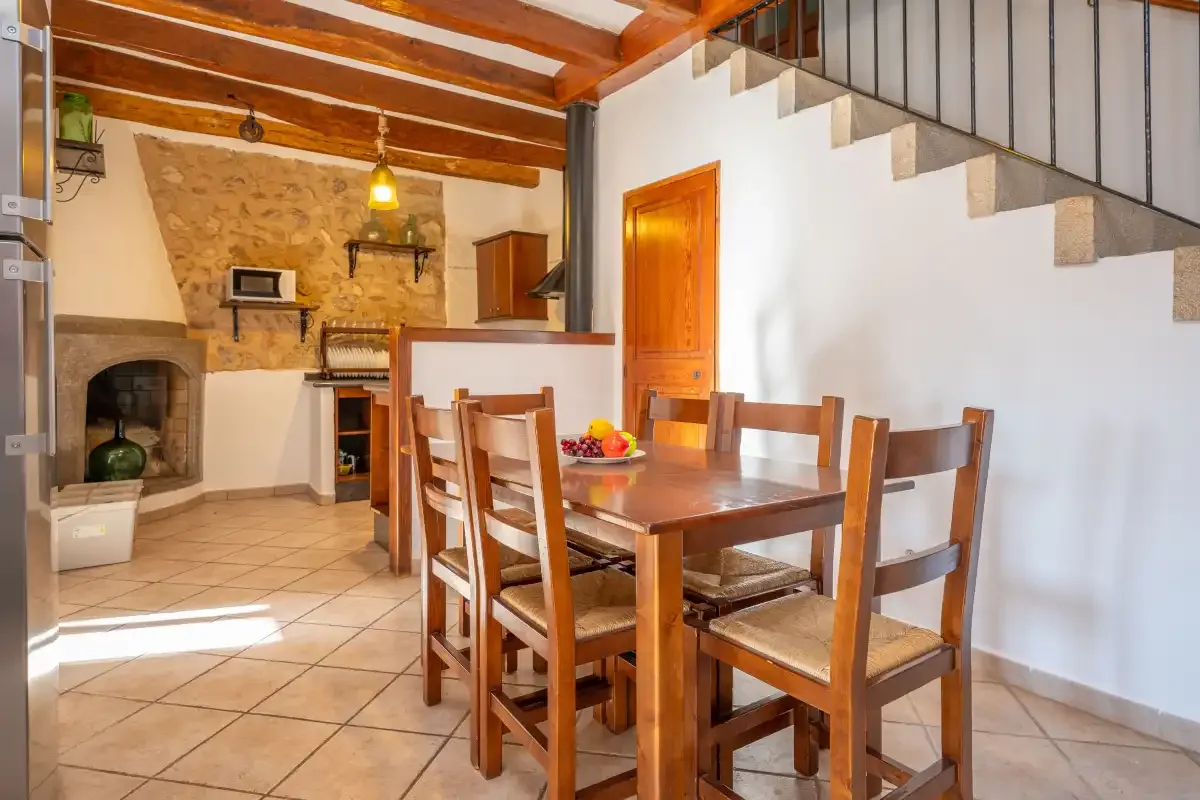 A dining area with a wooden table and chairs beneath an open staircase.