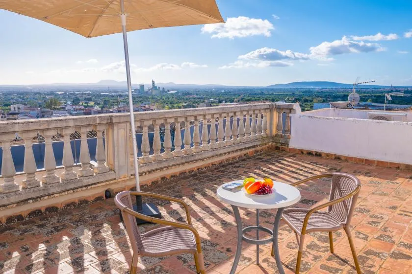 A rooftop terrace with a small table and seating overlooks the surrounding city.