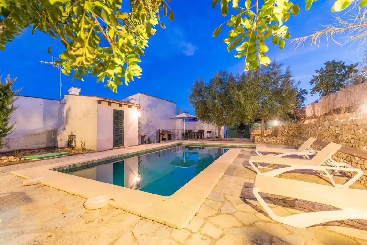 A swimming pool and lounge chairs sit in a paved outdoor courtyard.