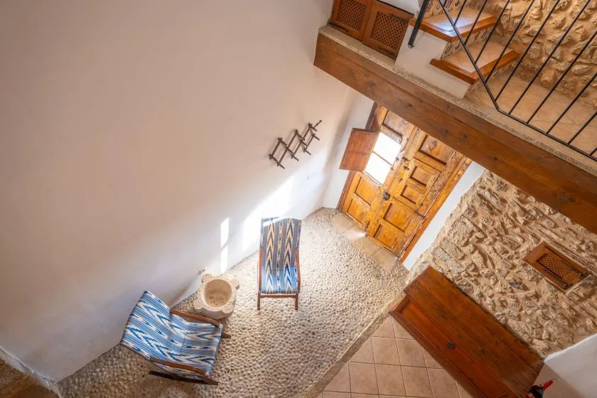A rustic interior with a pebble-patterned floor, wooden doors, and an upper railing.