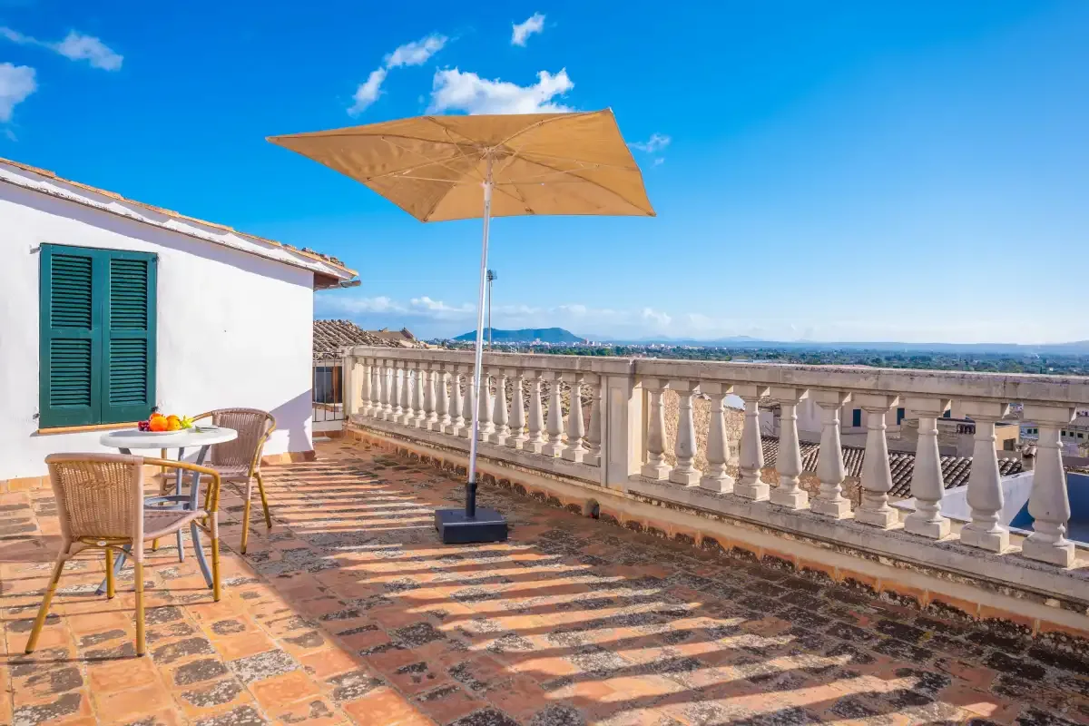 A sunny terrace with outdoor seating and a large parasol overlooks the surrounding landscape.