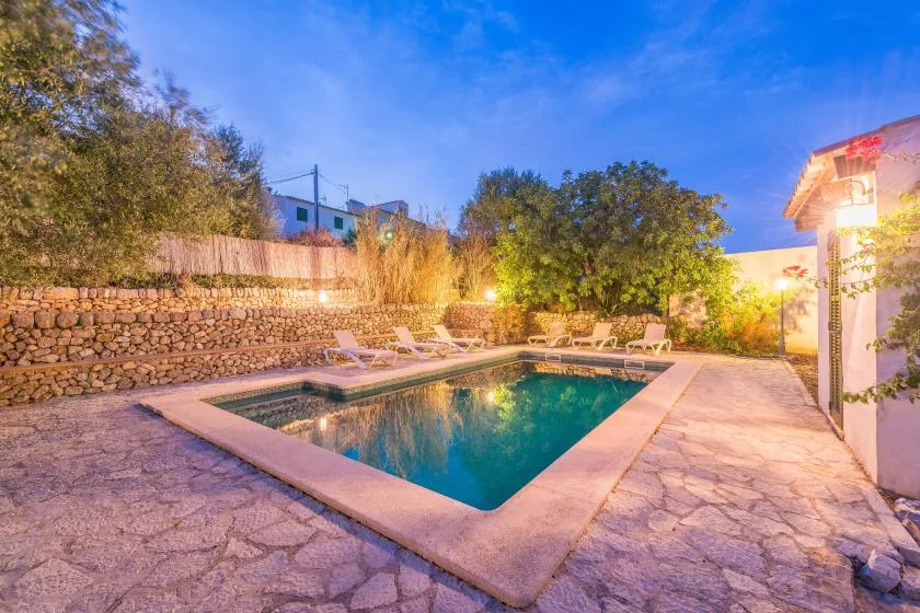 A swimming pool sits in a stone-paved outdoor courtyard surrounded by trees.