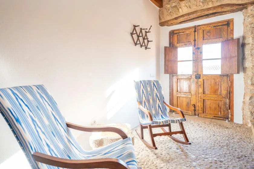 A bright room with two blue-striped seats beside a wooden window.