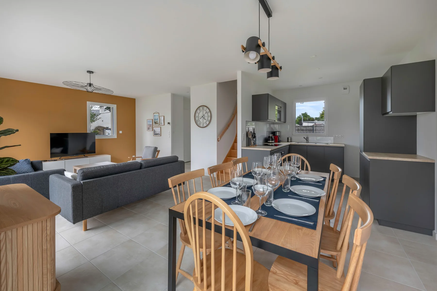 Open-plan dining and living area with a table, seating, and kitchen.