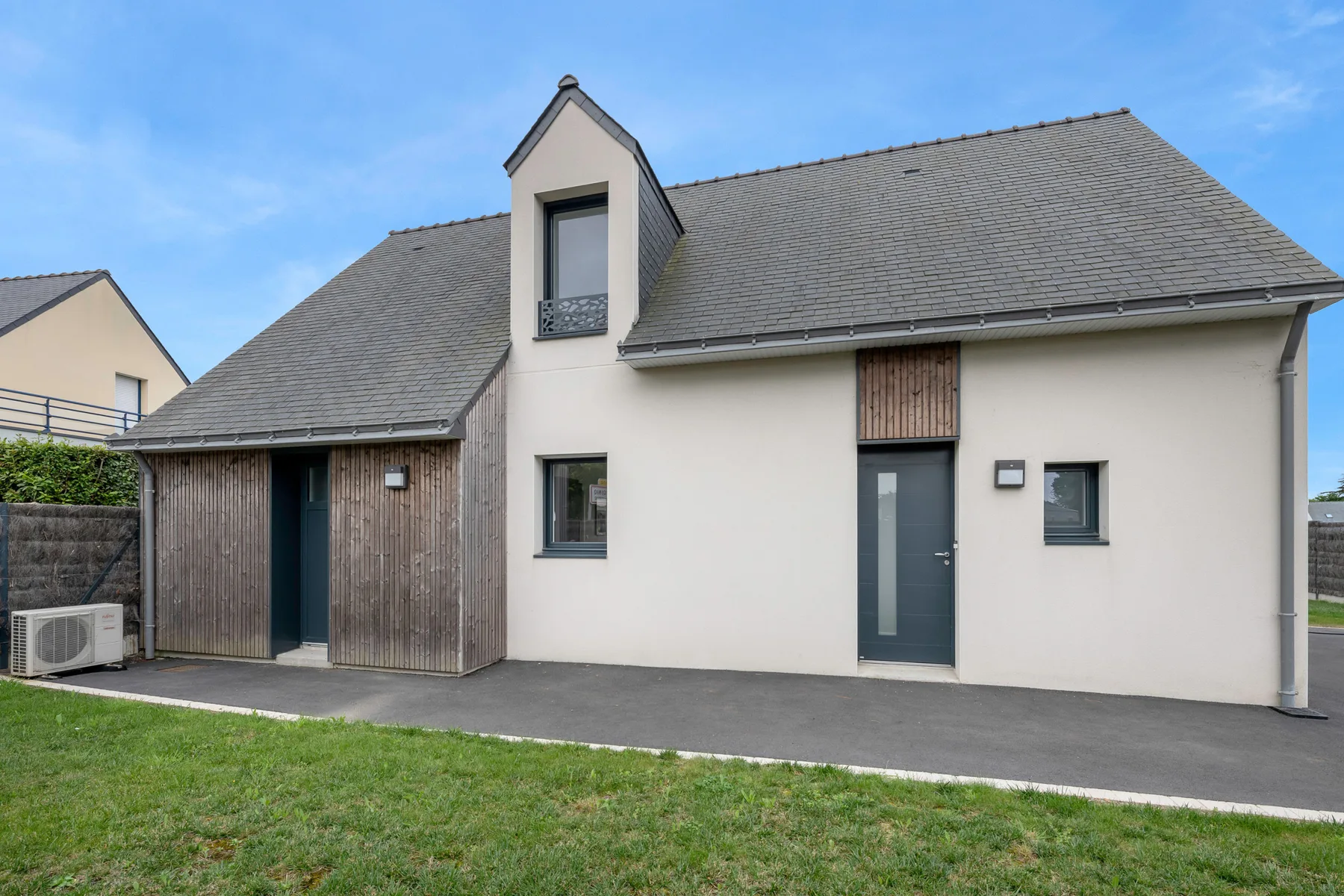 A modern house exterior with a dark front door and sloped roof.