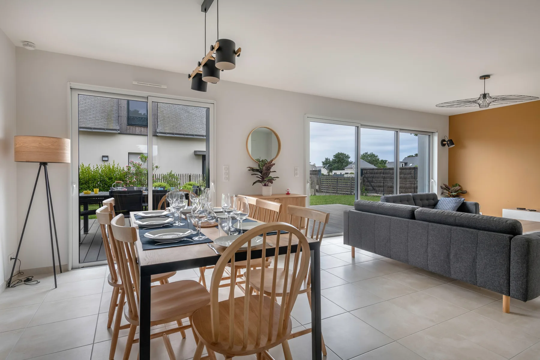 An open dining and living area with a table beside a gray sofa.