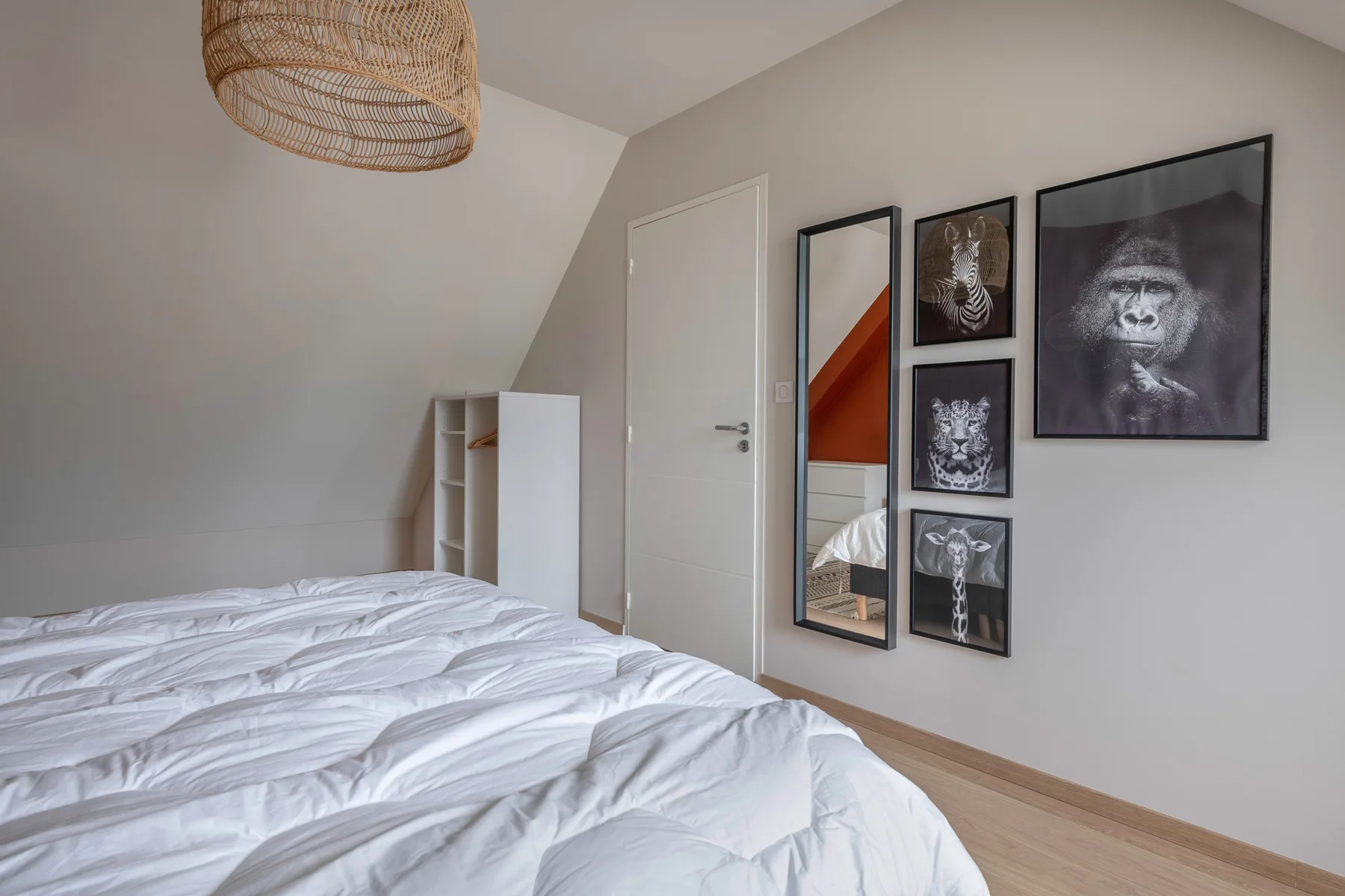 A bedroom with a rumpled bed and framed animal artwork on the wall.