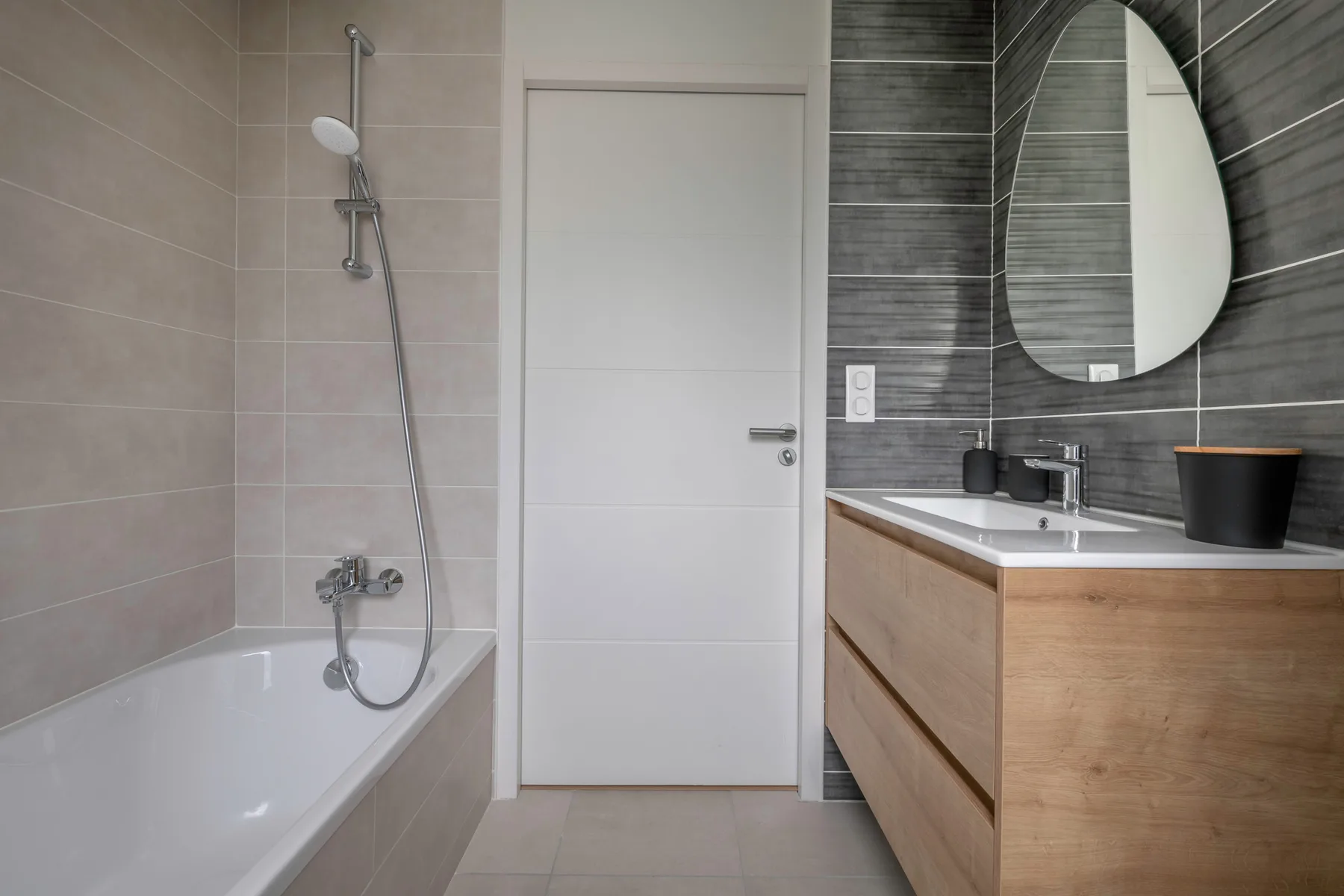 A bathroom with a bathtub, shower, and vanity beneath a wall mirror.