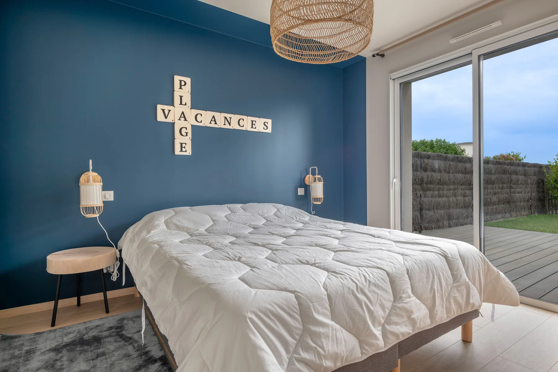 A bedroom with a bed against a blue wall and sliding glass doors.