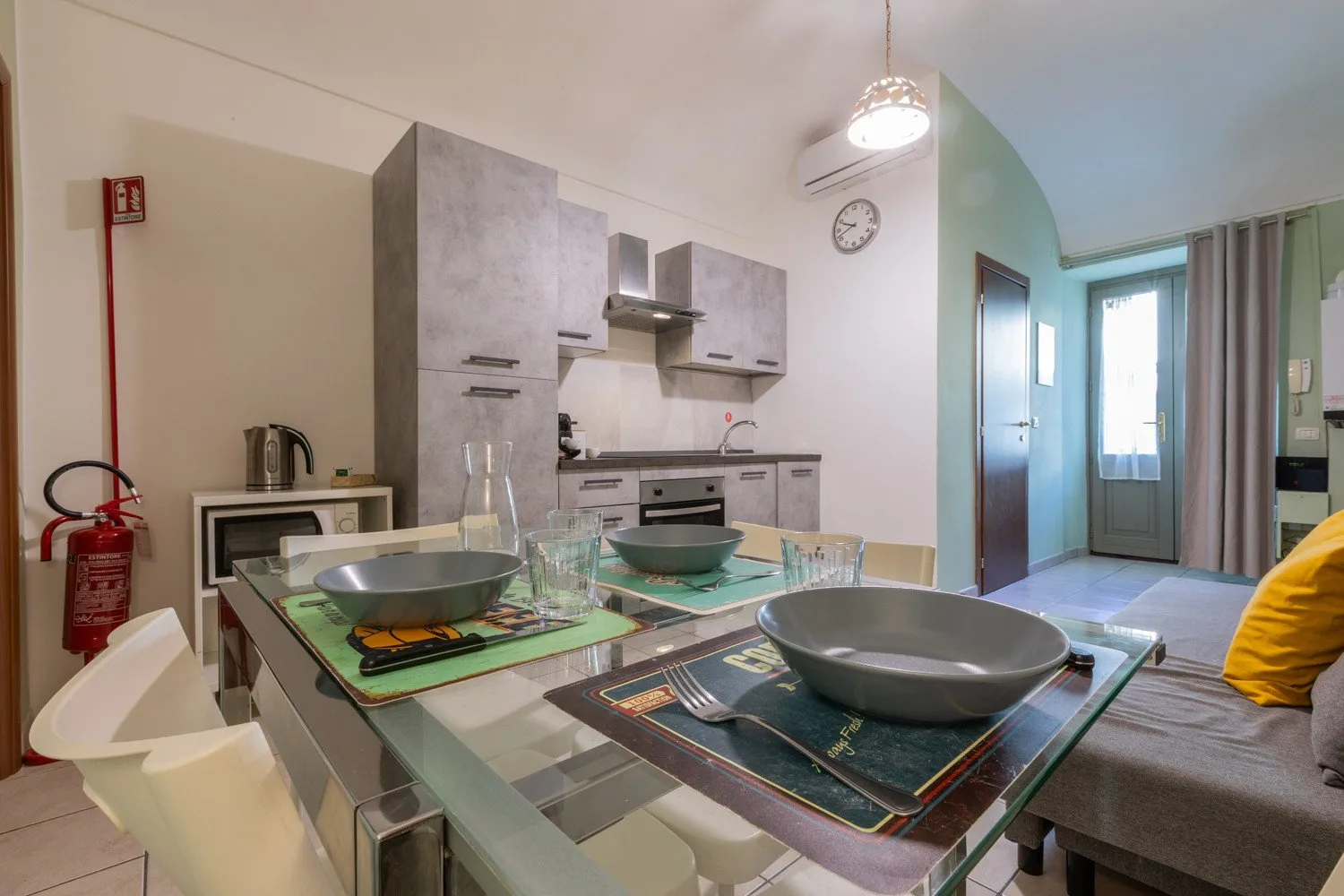 Un comedor con la mesa puesta está junto a una cocina compacta y un pasillo luminoso.
