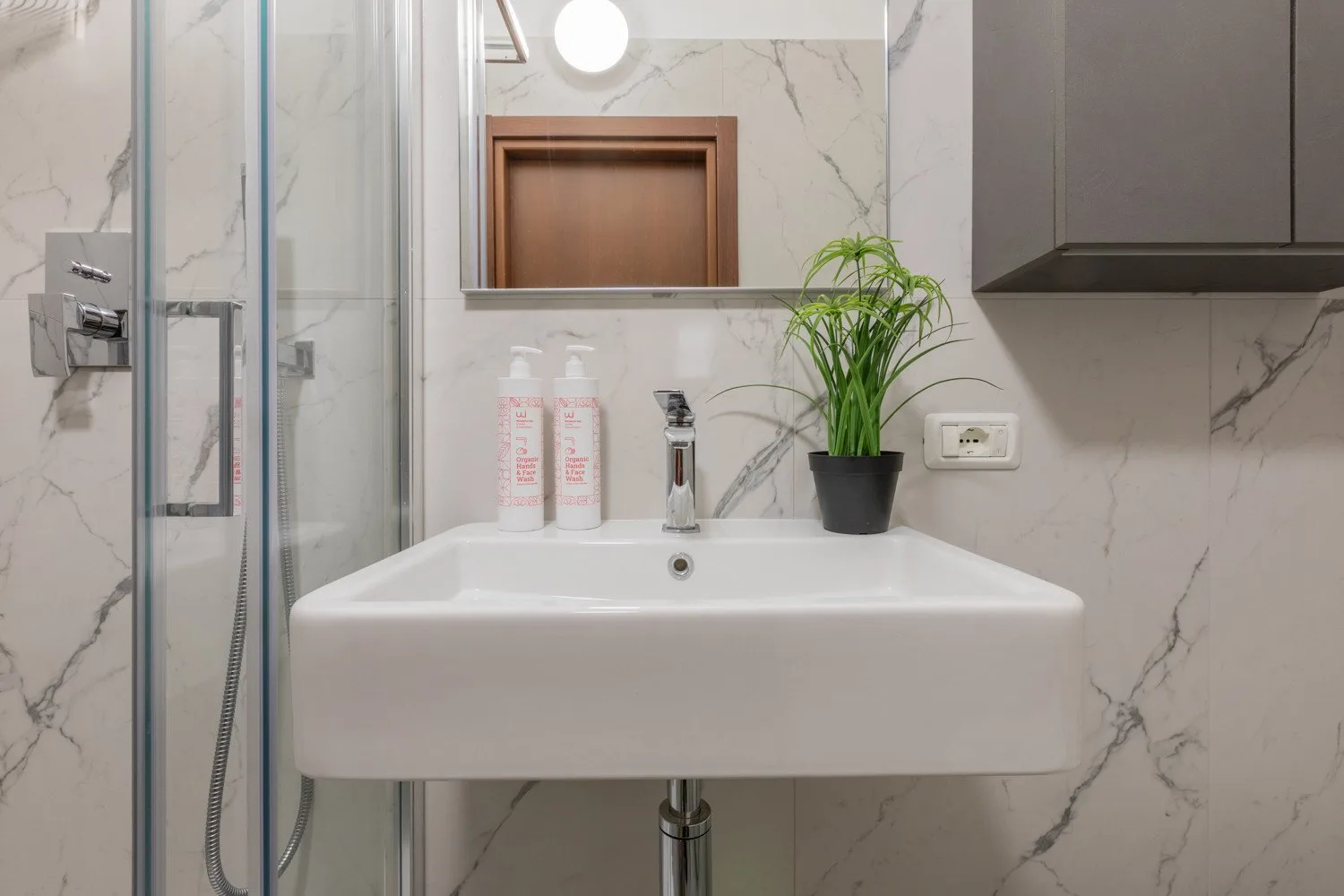 Un lavabo de baño con espejo y zona de ducha.