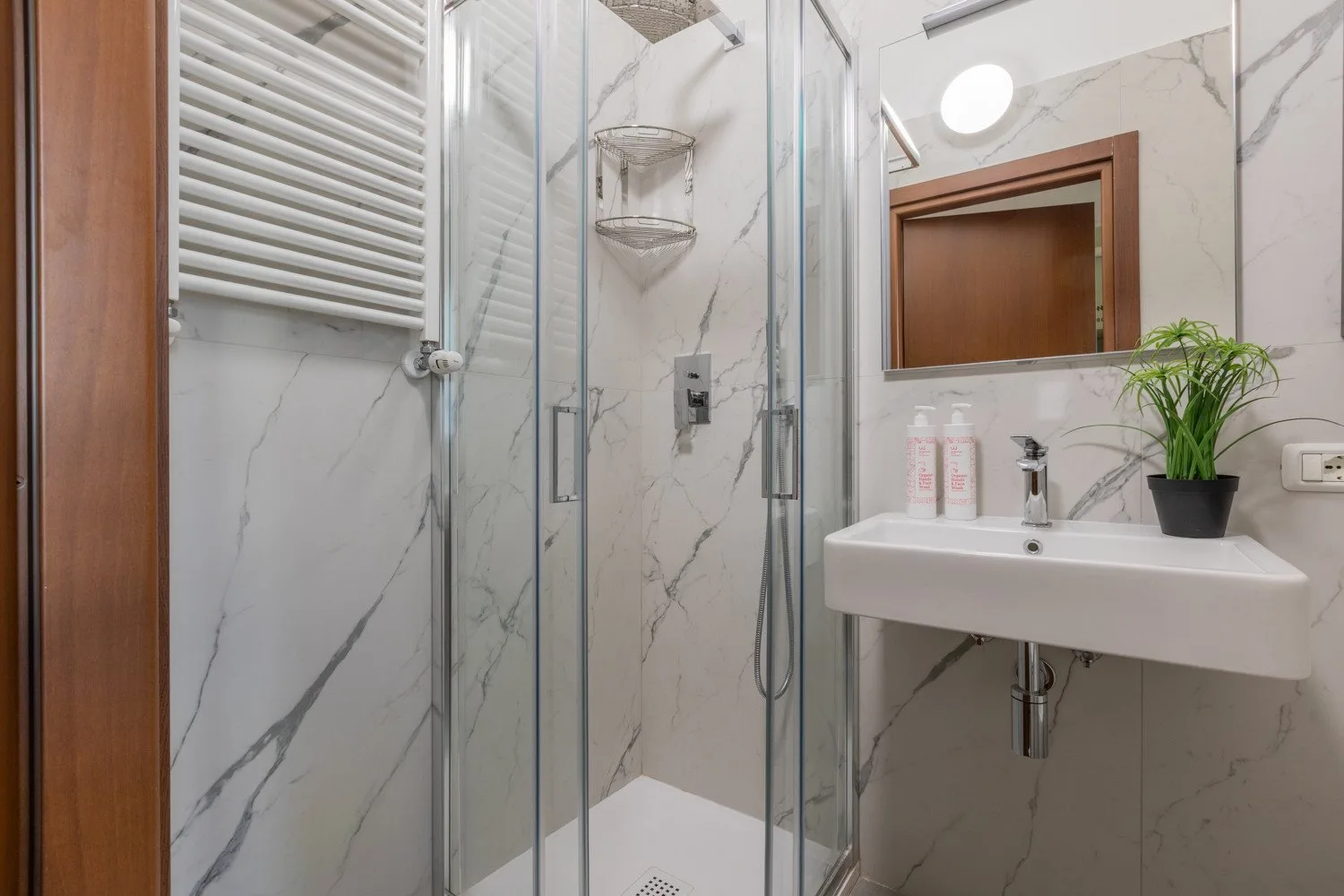 Un baño con una ducha de vidrio y un lavabo suspendido.