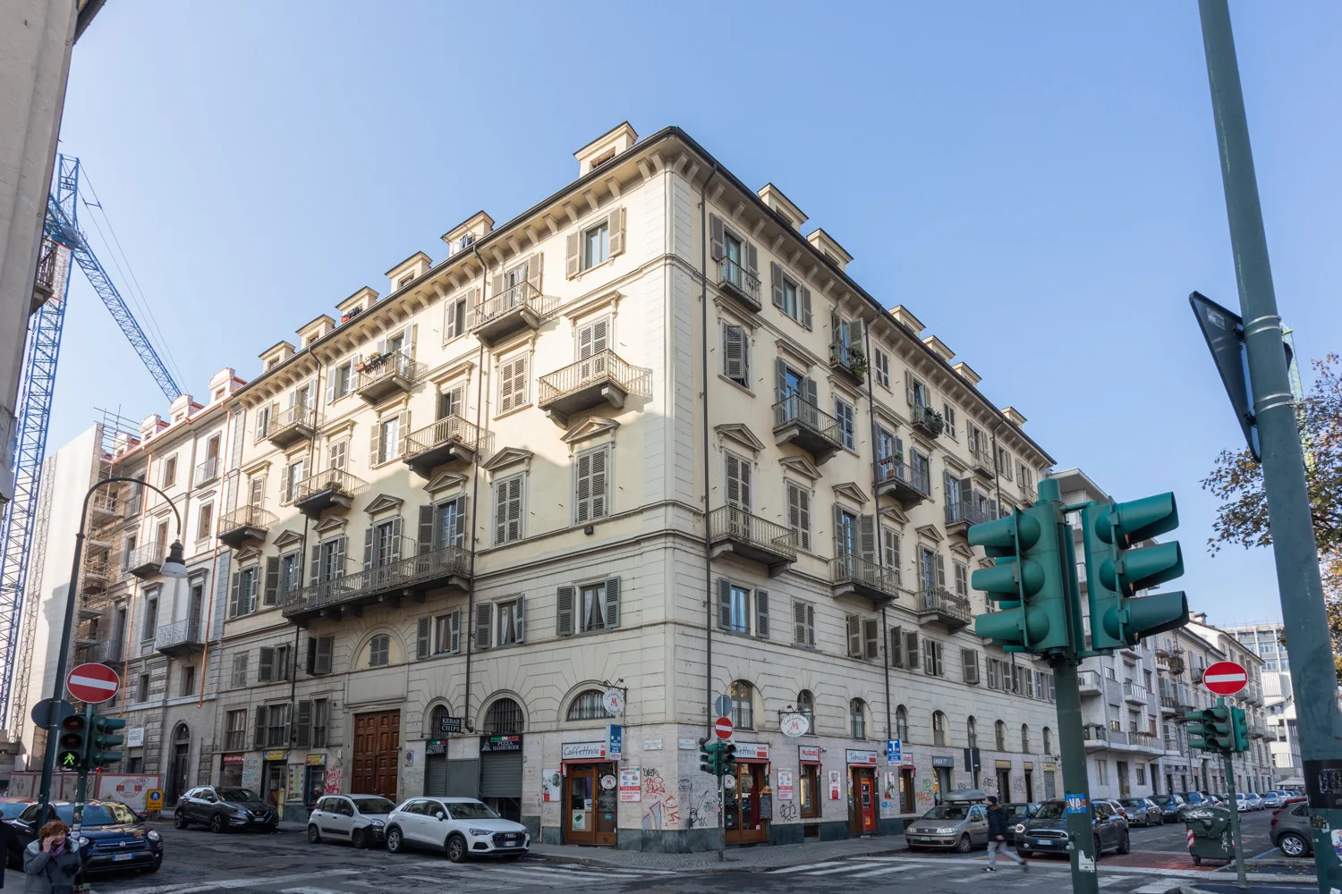 Un gran edificio de varias plantas con filas de ventanas ocupa una esquina urbana.