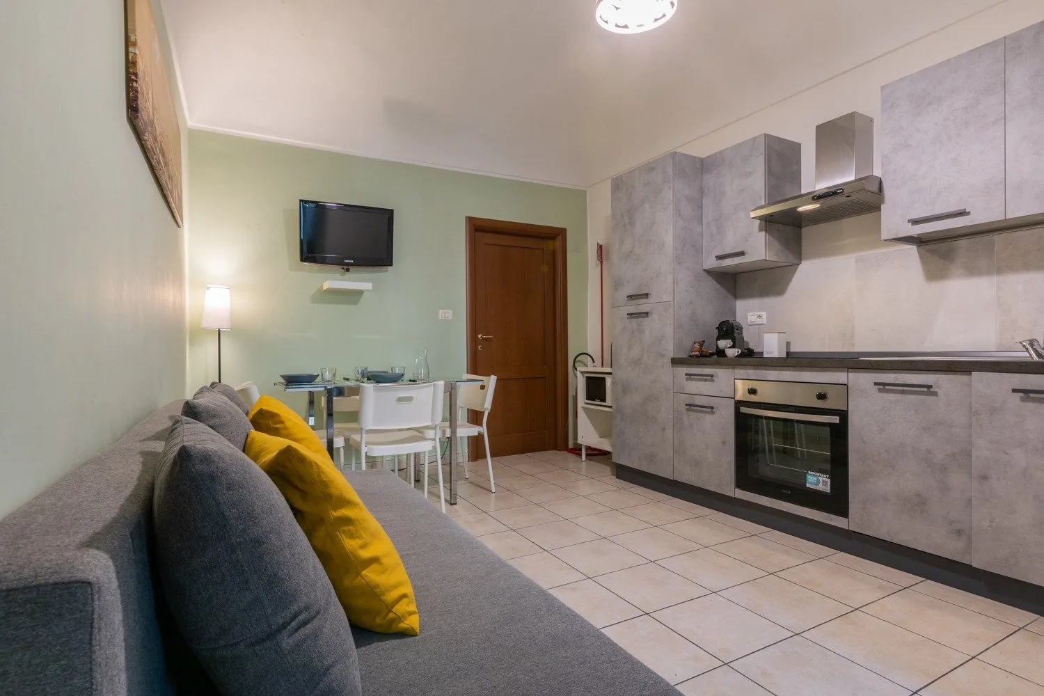 Una zona combinada de sala y cocina con una mesa de comedor y asientos grises.