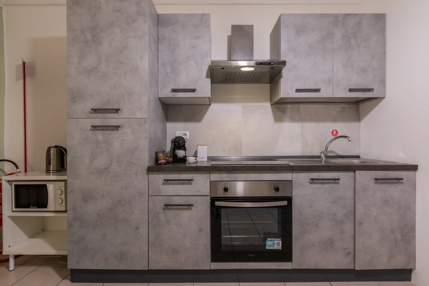Una cocina moderna con gabinetes grises, una placa de cocina y un horno.