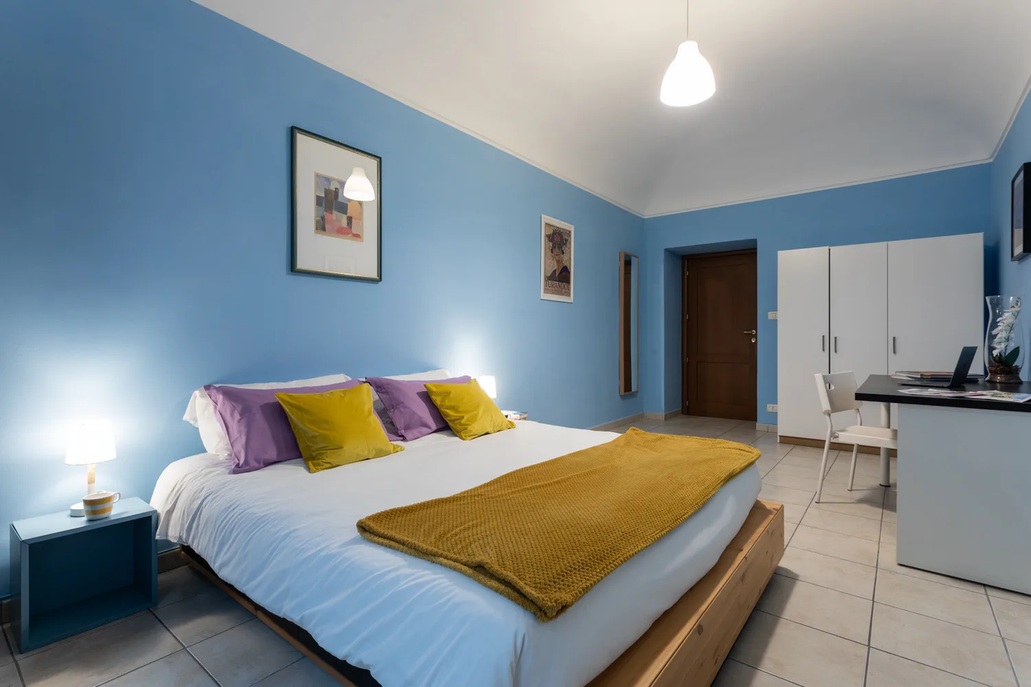 Un dormitorio con una cama grande, paredes azules y una zona de escritorio.