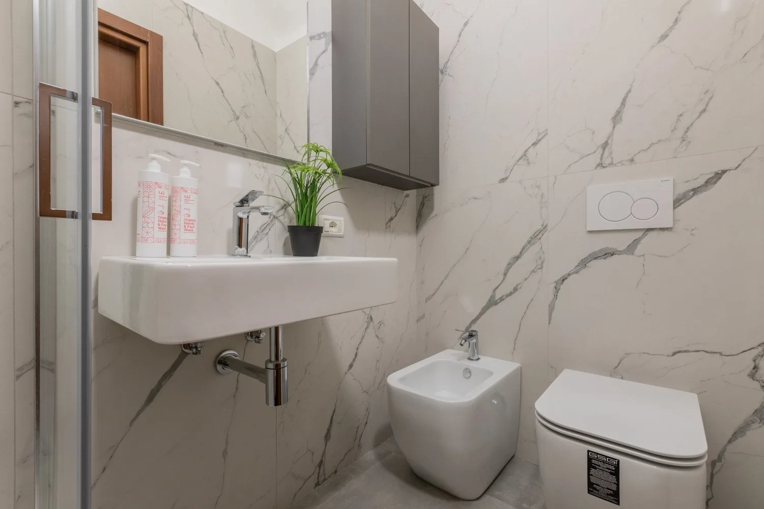 Un baño con lavabo suspendido, bidé e inodoro.