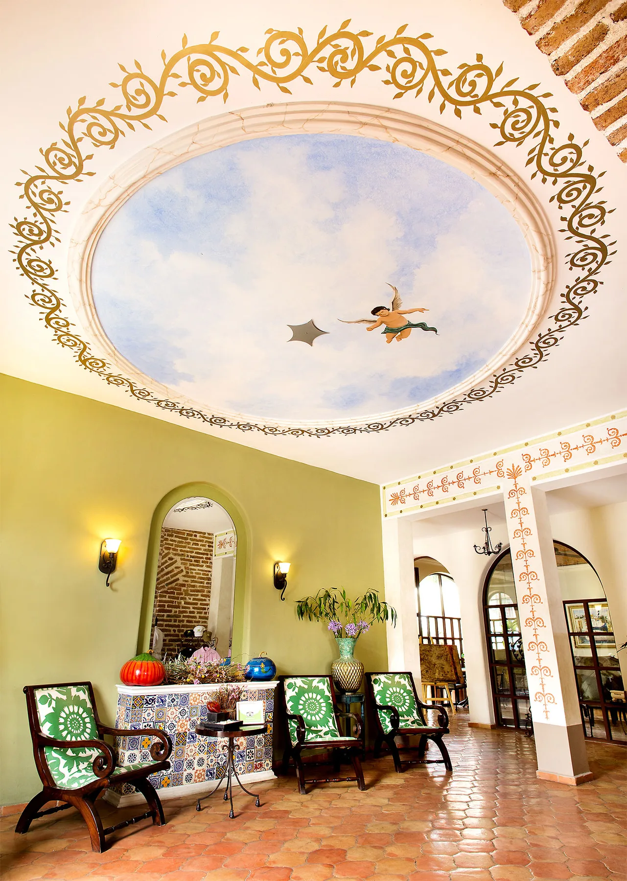 Área de estar del hotel con un espejo arqueado y un techo decorativo.