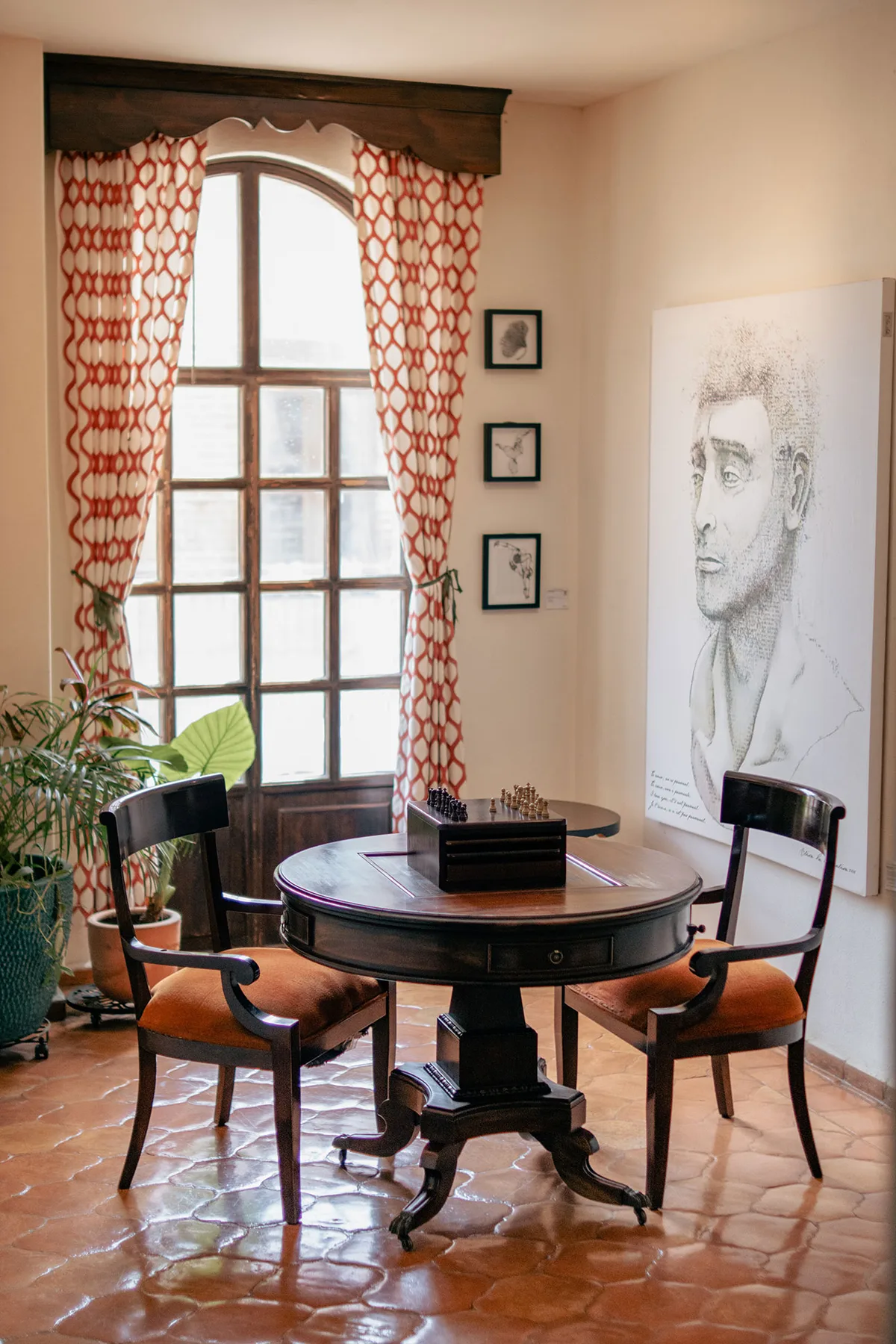 Área de estar del hotel con una mesa redonda, sillas, plantas y obras de arte.