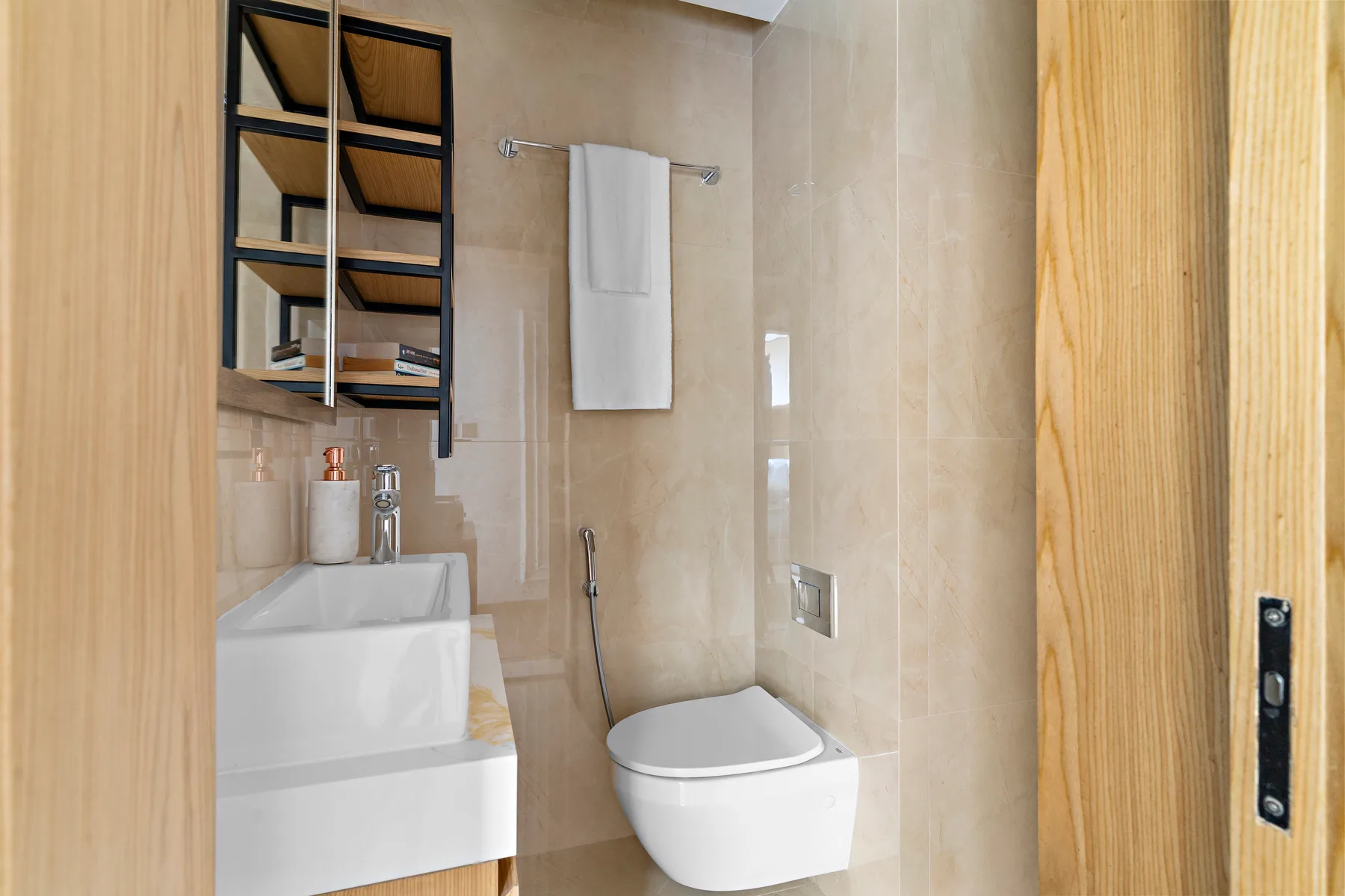 Un baño con azulejos, inodoro suspendido, lavabo y toallero.